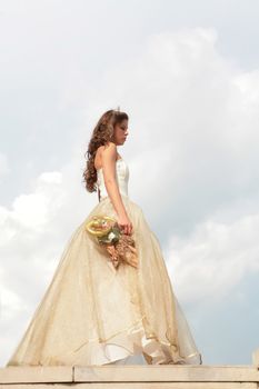 long-haired princess in golden gown with loved toy on background sky with cloud