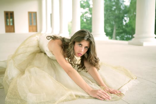 bride in golden gown on floor amongst pillars of the old-time building