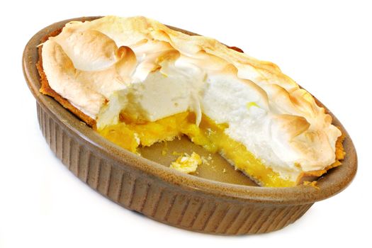 Home-baked lemon meringue pie, with a slice cut out.  Old-fashioned pottery pie plate, isolated on white.