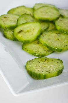 cucumber salad with dill in a white square plate