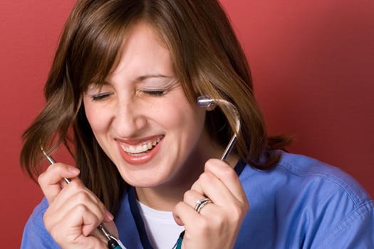 This nurse is laughing while using to her stethoscope.