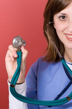 This nurse is holding up her stethoscope and smiling.