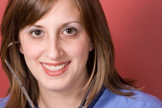 A closeup of a nurse smiling while using her stethoscope.