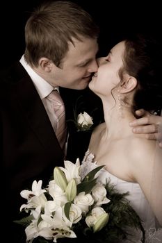 Bride and groom kissing on black background