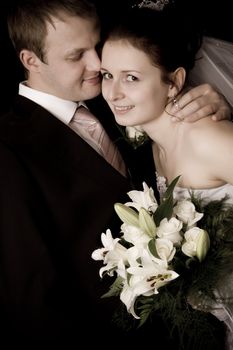 Bride and groom kissing on black background
