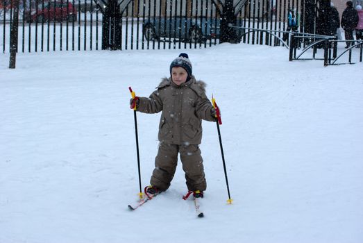 The boy in park skies during a snowfall