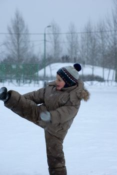 The boy plays in the street during a snowfall