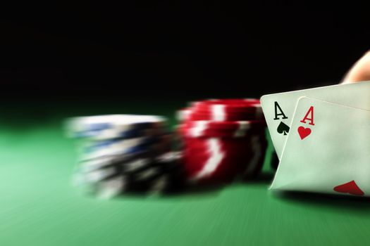 two aces on green table with blurry chips and background