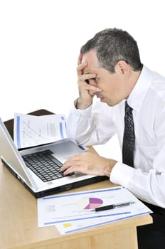 Stressed businessman sitting at his desk isolated on white background