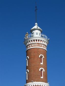 The historical memorial  the old tower for survey of fire with the dummy of a fireman on the blue sky background.Omsk,Russia