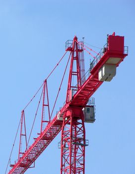 Tall red construction crane and blue sky