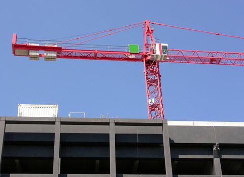 Tall red construction crane and blue sky