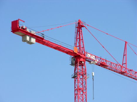 Tall red construction crane and blue sky