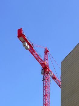 Tall red construction crane and blue sky