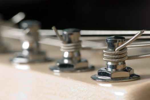 A macro shot of electric guitar machine heads used for tuning strings.