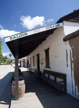 Old Town San Diego showing old saloon with barrels, stoop and seat bench along the adobe wall