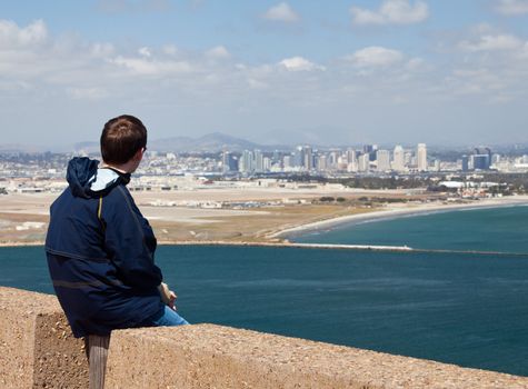 Skyline of San Diego in background behind Cabrillo monument on Point Loma with man overlooking the view