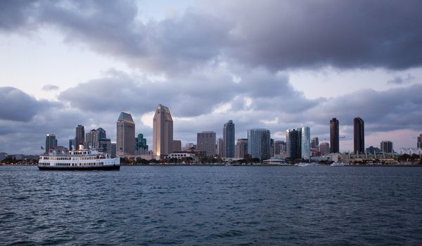 Sunset on San Diego skyline with city lights reflected in clouds taken from Coronado with ferry in foreground