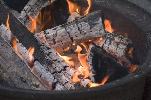 Hot coals of a campfire with flames.