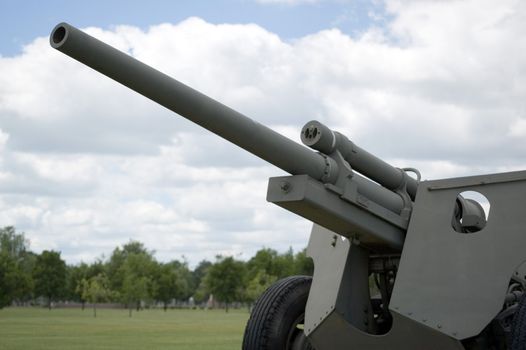 A military cannon against a cloud filled sky.