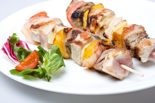 shashlik on a plate with a tomato and salad leaf