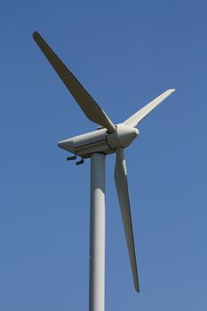 Green energy generating wind turbine in a blue sky