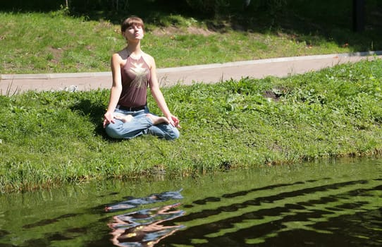 beautiful girl meditating near by water