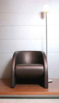 fragment of the interior, brown trendys leather easy chair with floor lamp near gray wall