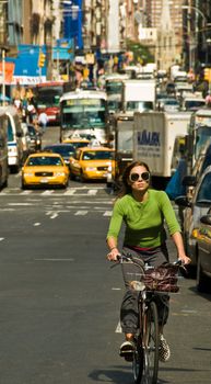 woman on bike with dense traffic behind.  Mid-town NYC