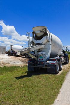 Cement trucks on a job site with block home in background