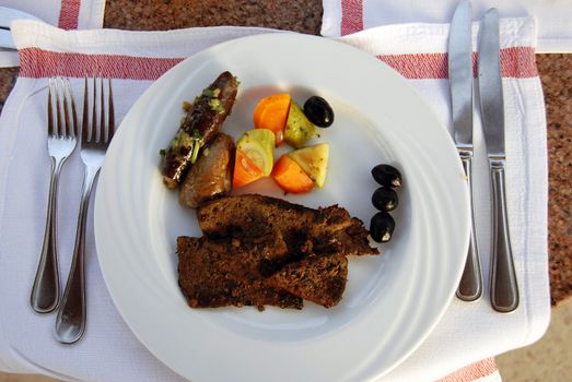 roasted liver served on white plate with vegetables on dinner table