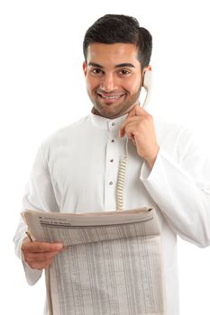 An ethnic italian / arab mixed race businessmanwearing traditional middle eastern clothing.  He is on the telephone and holding a newspaper at finance section.  White background.