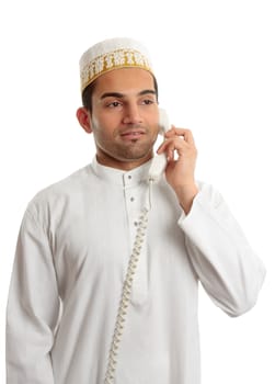 An arab italian mixed race businessman on the telephone.  He is wearing a traditional white middle eastern robe eg Kurta or dishdasha and a white hat called a topi.  White background.