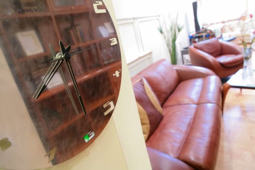 wall clock in interior of the drawing room with leather sofa