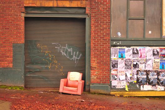 brick wall, posters, and torn red chair