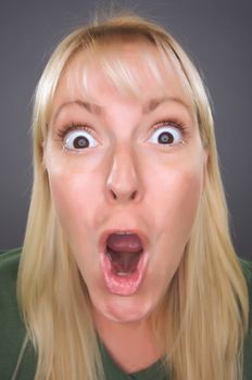 Shocked Blond Woman with Funny Face against a Grey Background