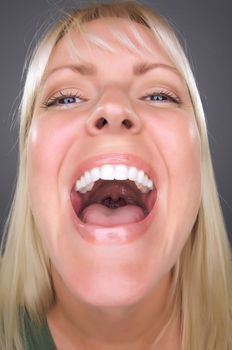 Laughing Blond Woman with Funny Face against a Grey Background.