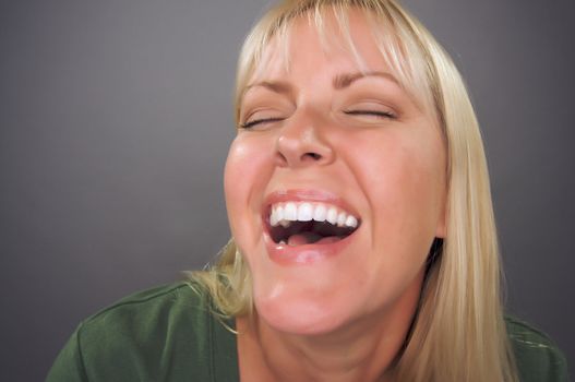 Beautiful Blond Woman Laughing Against a Grey Background.