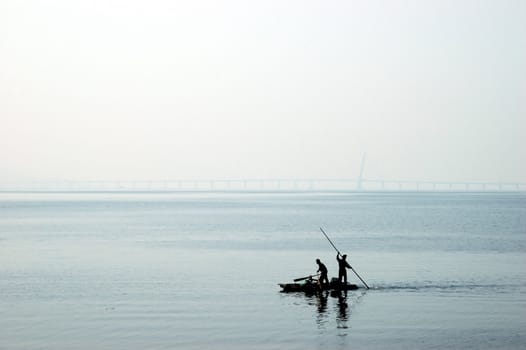 South China Sea with harbour between Shenzhen and Hongkong. Small boat on first plan and far behind bridge connecting China and Hongkong.