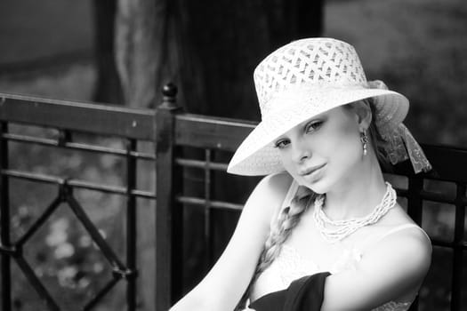 Young lady wearing white hat sitting on bench in park