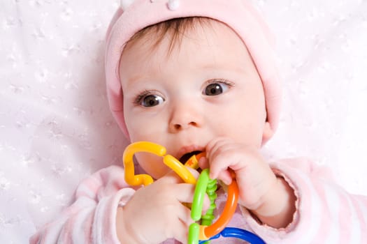 Portrait of Baby with vibrant chain toy wearing hat