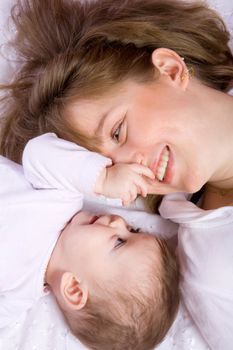 Happy Mother playing with seven month baby lying on floor