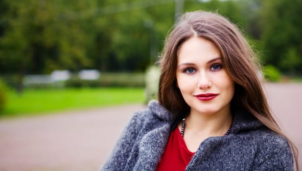 Pensive young womanstanding in park looking at you