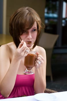 Young Woman tasting hot chocolate at table outdoors