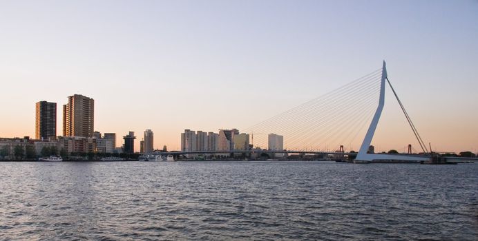 View on Erasmusbridge in Rotterdam with residential- and office buildings on a summer evening