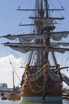 Frontside of old sailingship with modern buildings in the background