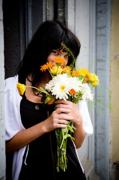 Girl with bouquet standing near door hiding face