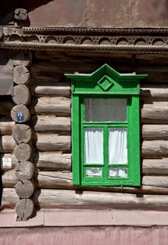 Old window in the log house. Close-up, a fragment of the facade. Russian province.