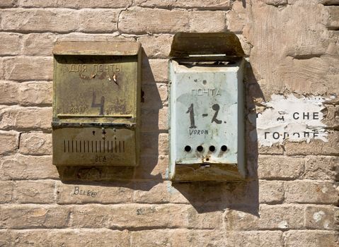 The old brick wall with mailboxes. Rusty metal and old brickwork. Close-up, fragment.