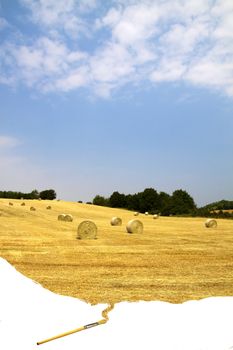 Brush painting a landscape of a field with bales of hay